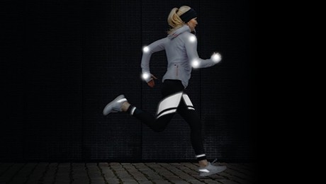 女运动员身着带有反光装饰的运动服跑步